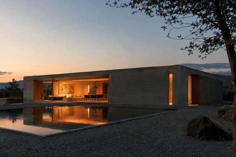 Concrete pavilion at dusk with warm interior light